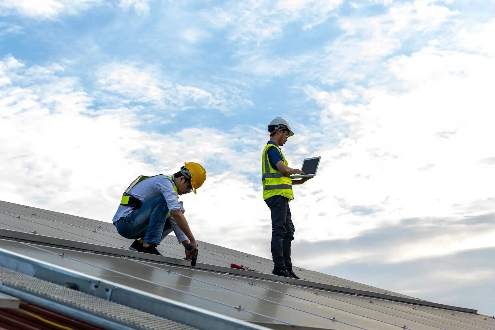 Roofing contractors working on roof installation while project manager reviews plans, showing cost per lead for roofing contractors.